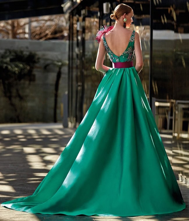 Robe de soirée verte longue avec décolleté en V et détails en paillettes, portée par une femme dans un environnement urbain, mettant en valeur un style sophistiqué et glamour.