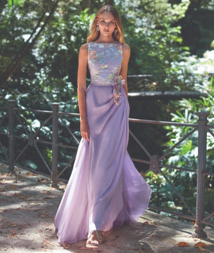 Balade en robe longue violette avec broderies florales et ceinture en tissu.