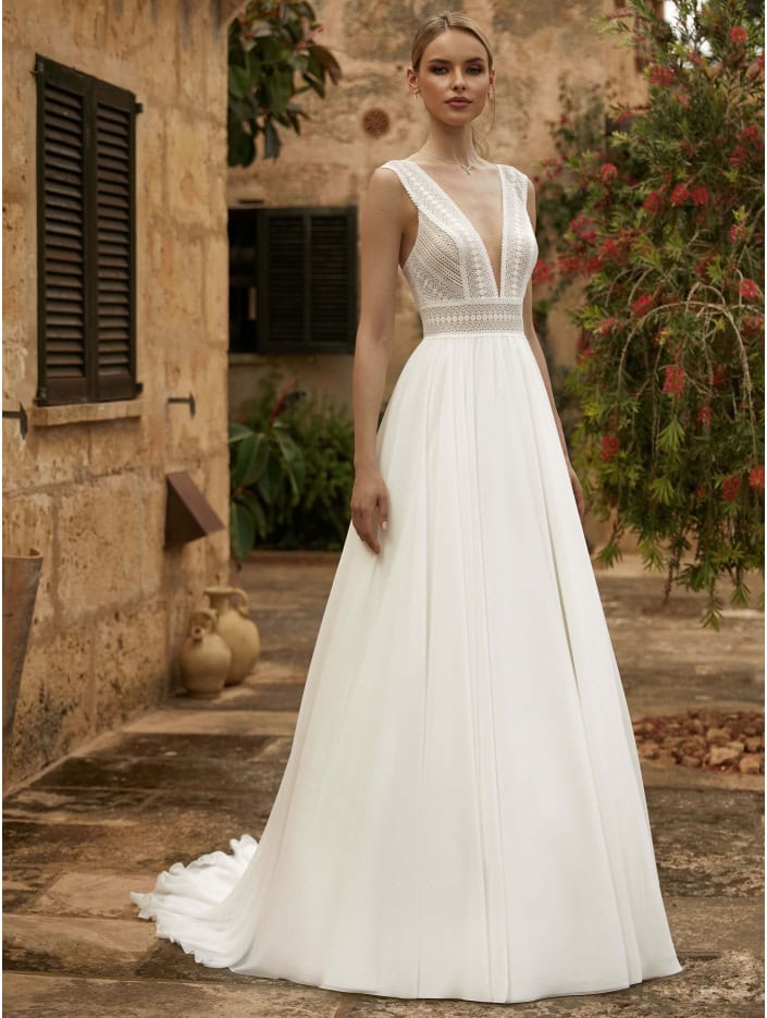 Vêtement de mariée blanc avec détails en dentelle, parfait pour un mariage bohème ou champêtre, mettant en valeur la silhouette avec un design fluide et sophistiqué.