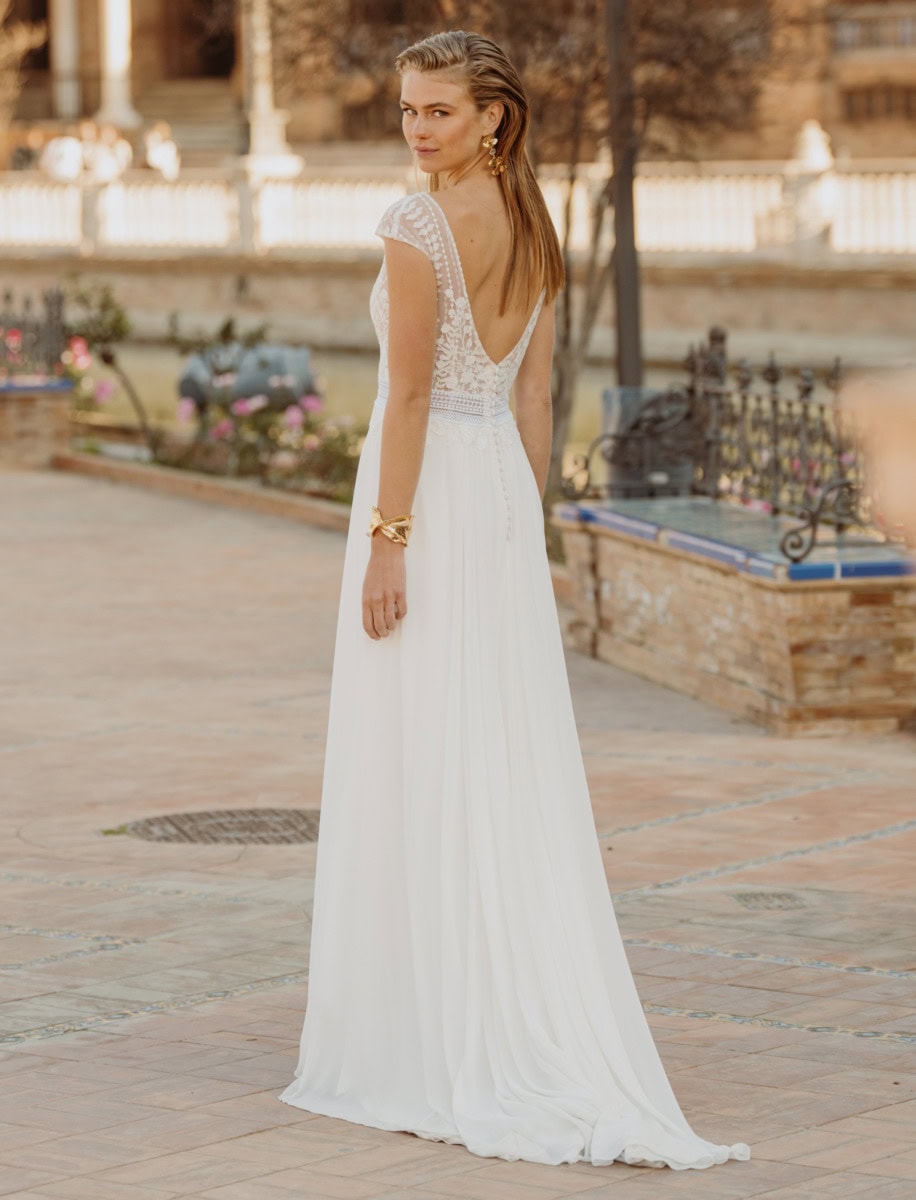 Robe de soirée élégante blanche avec détails en dentelle, portée par une femme dans un parc urbain, ambiance romantique et sophistiquée, idéale pour événements formels ou mariages.