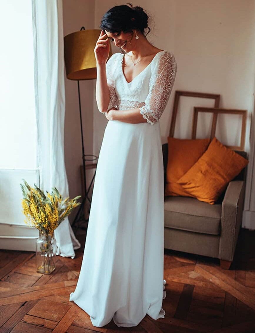 Blandine-face-Elsa-Gary-robe-de-mariee-A-line-trapeze-fluide-top-decollete-V-dentelle-manches-transparence-de-dentelle-longueur-34-traine-magasin-de-robes-de-mariee-Annecy
