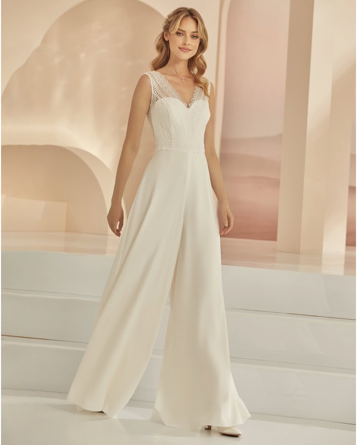 Tage de mariage élégants avec une robe blanche à manches en dentelle et pantalon large, parfaite pour une mariée moderne et sophistiquée. Style chic et tendance pour une occasion spéciale.
