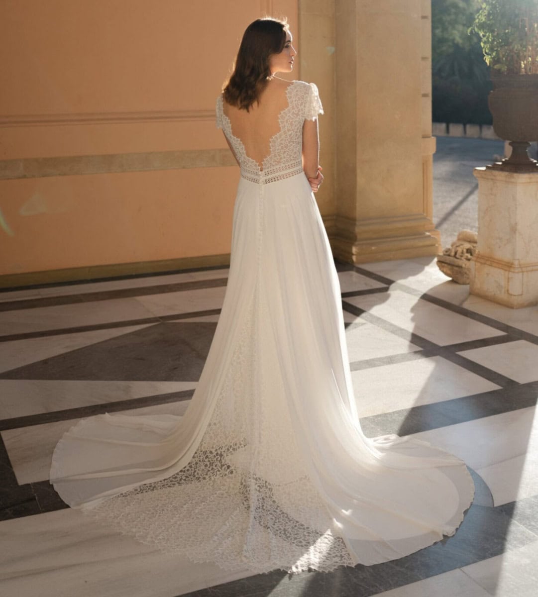 Vêtement de mariée blanc avec dentelle élégante, porté par une femme dans un lieu historique en plein air, lumière naturelle, style romantique et sophistiqué, parfait pour une occasion spécial.