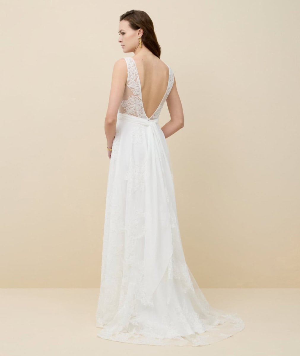 Robe de mariée en dentelle blanche avec dos en V profond, idéale pour un mariage romantique et sophistiqué. Conçue pour mettre en valeur la silhouette de la mariée avec finesse et élégance.