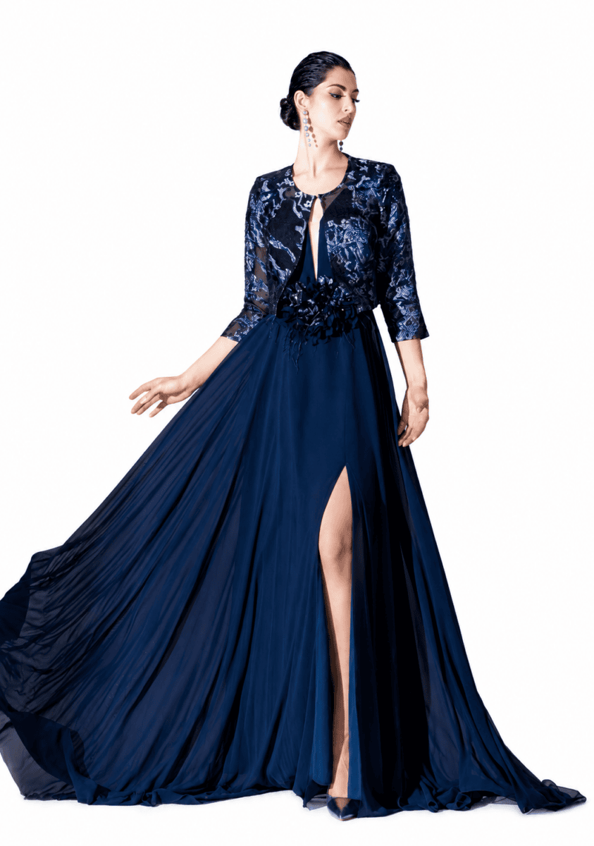 Robe de soirée élégante en bleu marine avec jupe plissée et fente haute, portée par une mannequin avec accessoires sophistiqués.