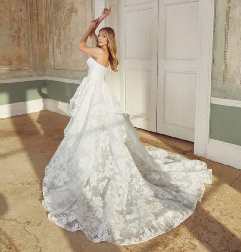 Robe de mariée blanche avec traîne longue, idéale pour un mariage élégant, mettant en valeur la silhouette de la mariée dans un décor vintage.