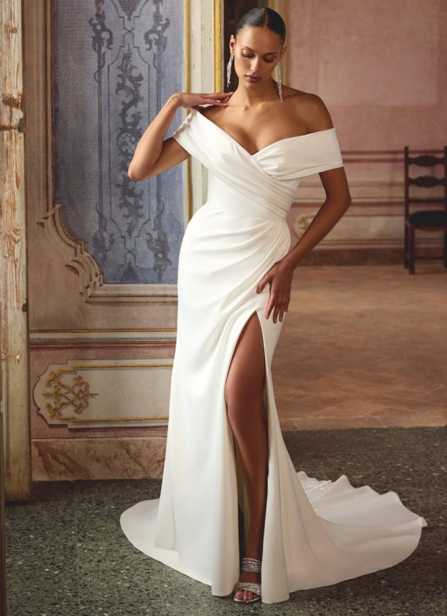 Modèle portant une robe de soirée blanche avec décolleté et fente haute, dans un décor sophistiqué, mettant en valeur son style chic et moderne.