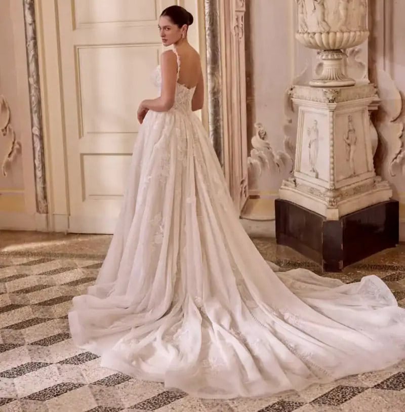 Robe de mariée en satin ivoire avec longue traîne, élégante et sophistiquée, portée par une modèle dans un décor classique. Parfaite pour un mariage chic et romantique.