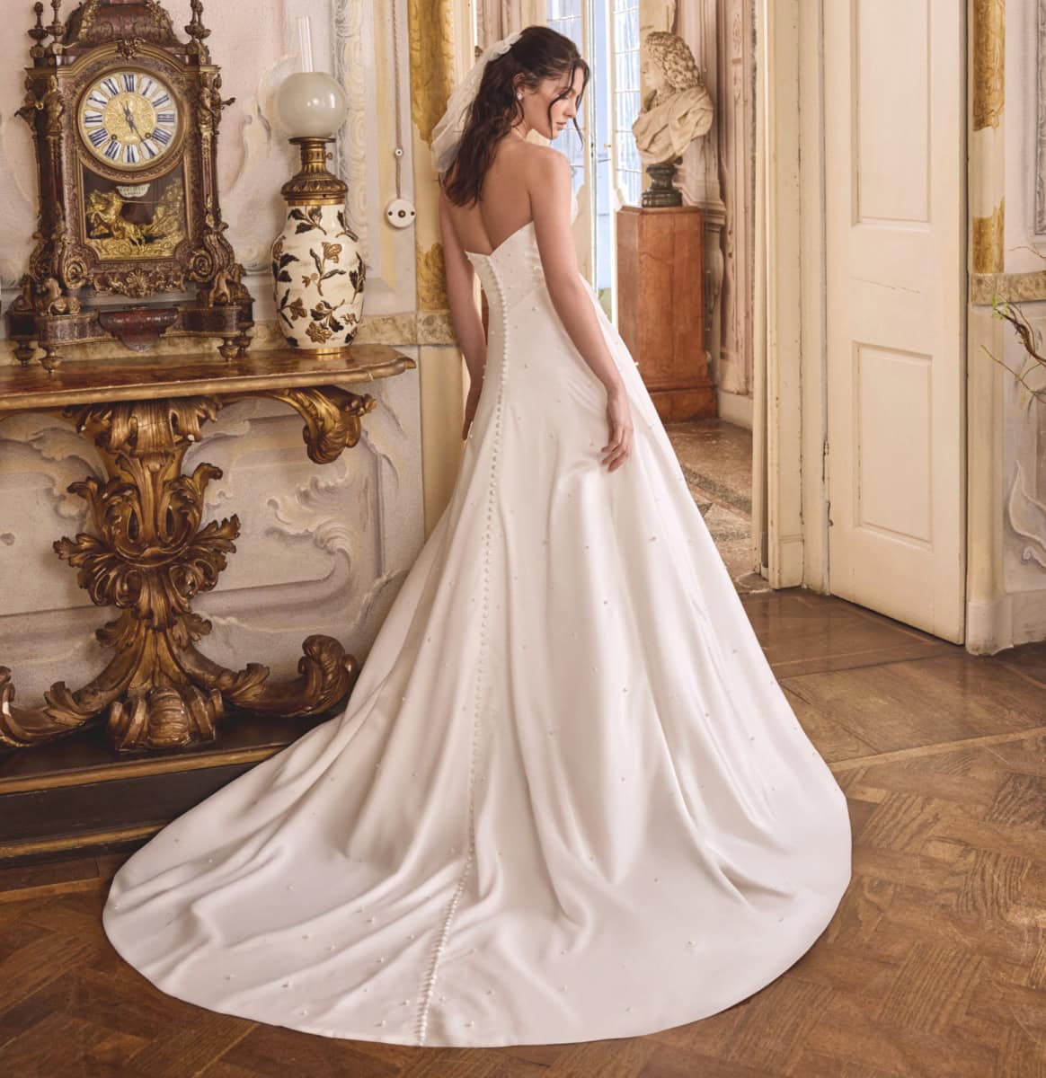 Vêtement de mariée blanc avec traîne longue, parfait pour un mariage élégant, dans un décor vintage avec mobilier ancien et décoration raffinée.