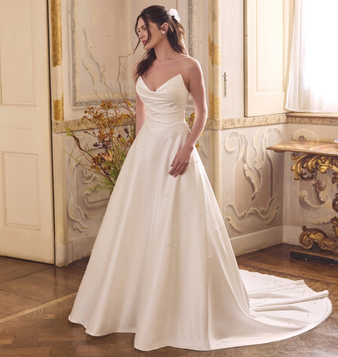 Robe de mariée blanche élégante avec décolleté en cœur, parfaite pour un mariage romantique, mettant en valeur la silhouette de Lizzie dans un décor classique et sophistiqué.