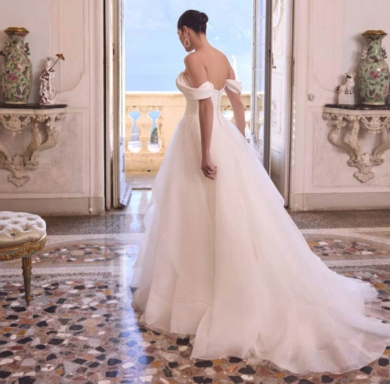 Vêtement de mariée blanc avec décolleté et manches épaules dénudées, parfait pour une occasion spéciale. Conçu pour mettre en valeur la silhouette avec un style classique et chic.