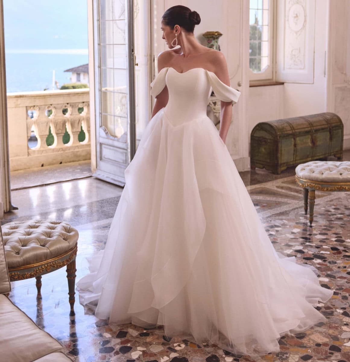Robe de mariée blanche avec épaules dénudées et jupe volumineuse, parfaite pour un mariage chic et sophistiqué.