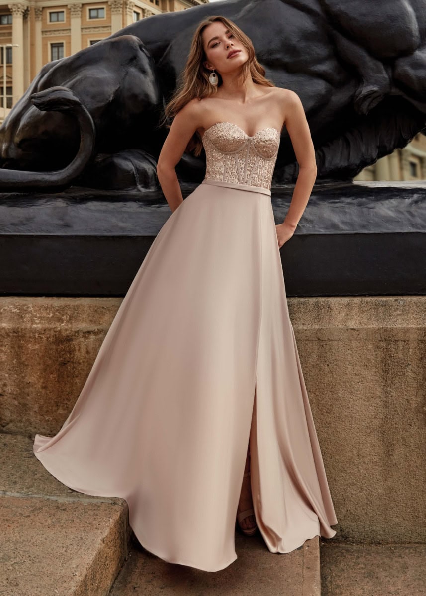 Robe de soirée longue beige avec bustier en dentelle et jupe fluide, idéale pour événements formels ou mariages, mettant en valeur la silhouette avec style et élégance.