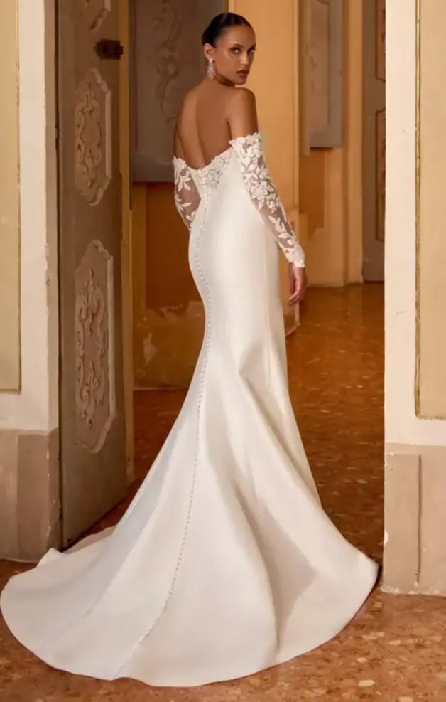 Robe de mariée blanche avec manches en dentelle et décolleté épaule, longue traîne, parfaite pour une occasion spéciale.