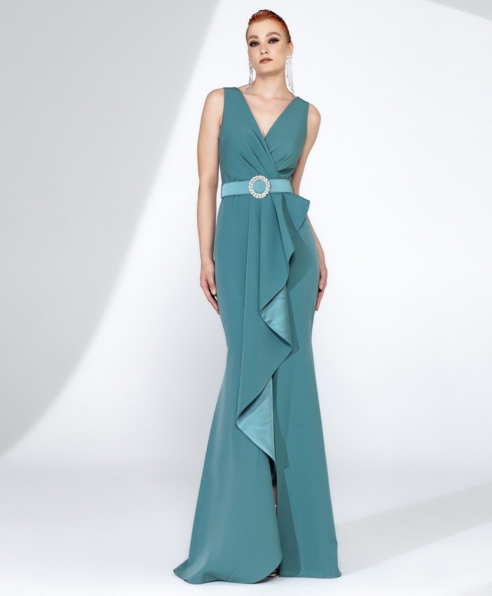 Baladez-vous avec cette robe longue turquoise élégante, parfaite pour une occasion spéciale, mettant en valeur votre silhouette avec un design sophistiqué et une ceinture à bijoux scintillante.