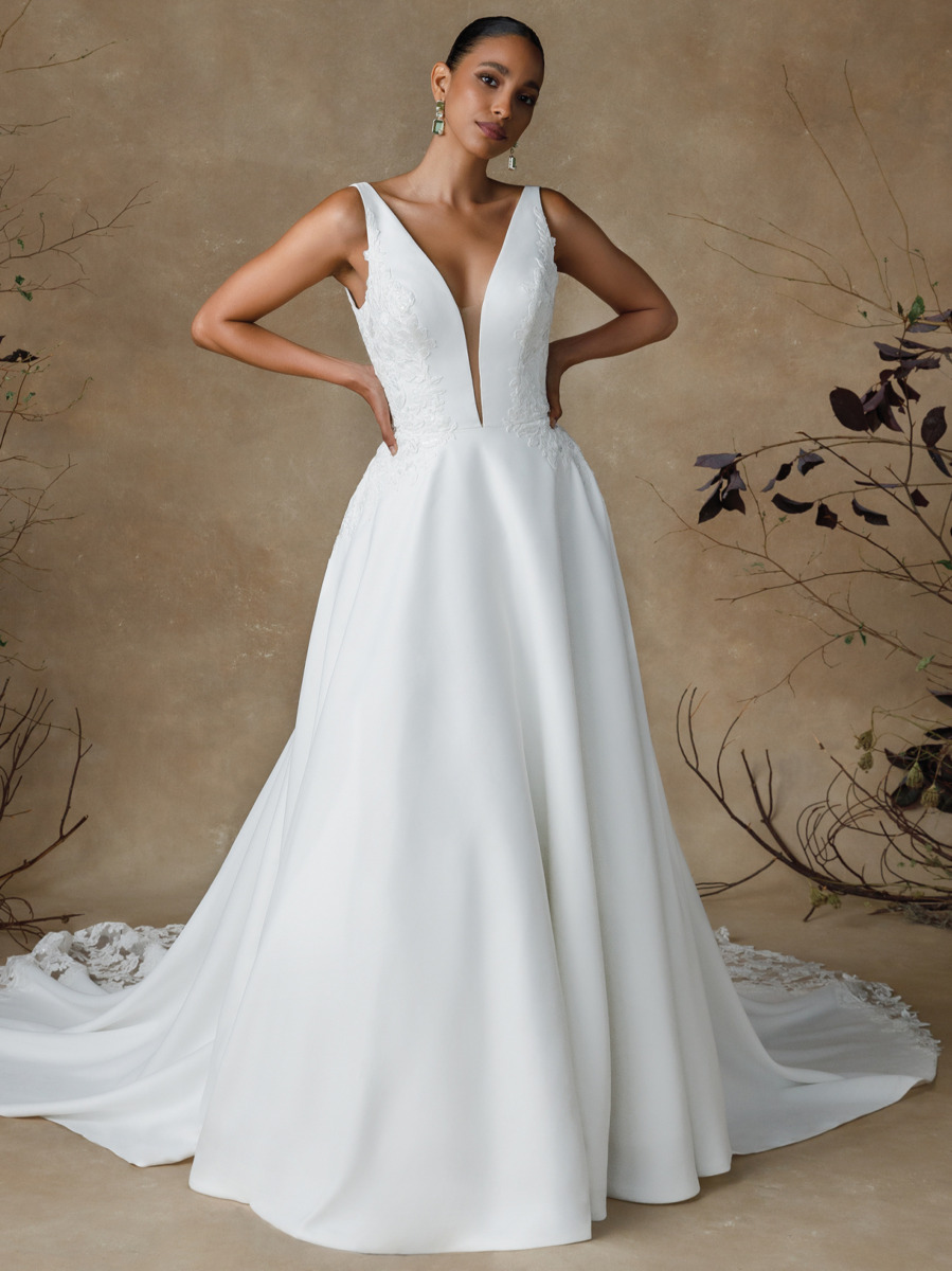 Robe de mariée Gibson blanche avec décolleté profond et détails en dentelle, portée par un modèle dans un décor naturel minimaliste.