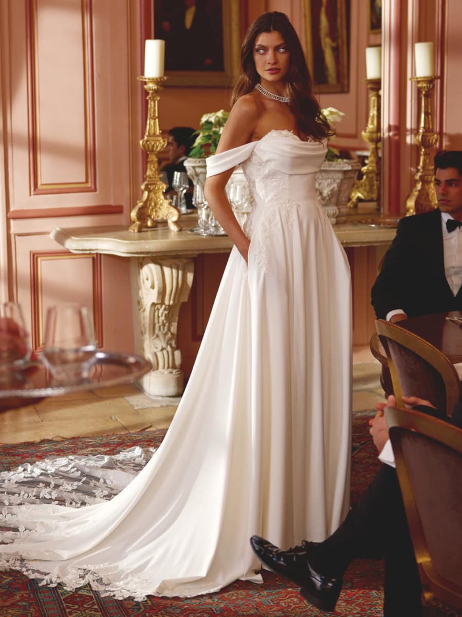 Robe de mariée en satin blanc avec décolleté en cœur et manches courtes, portée par une femme lors d'une cérémonie dans un cadre luxueux.