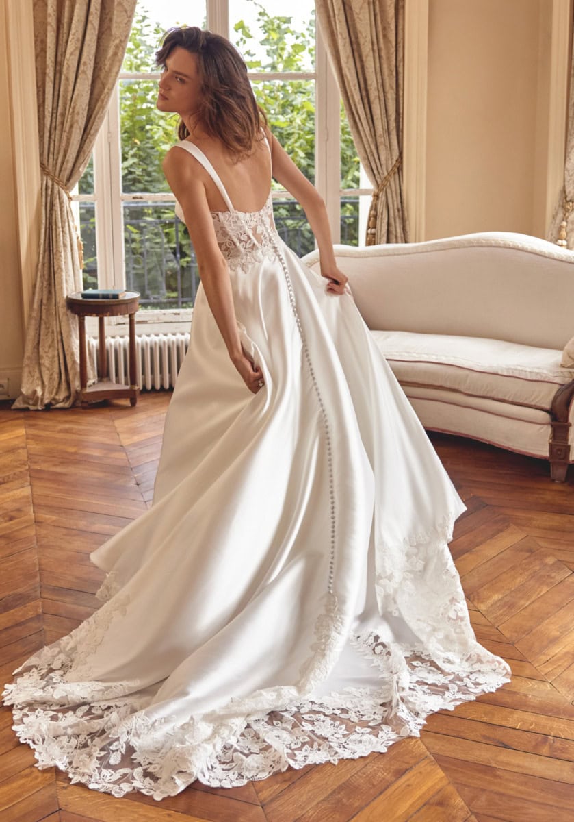 Robe de mariée blanche avec dentelle, corsage ajusté et longue traîne en dentelle, idéale pour un mariage romantique. Parfaite pour les mariées recherchant élégance et sophistication.
