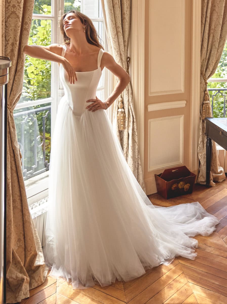 Robe de mariée blanche longue avec bustier ajusté et jupe en tulle fluide, idéale pour une mariée moderne et sophistiquée. Parfaite pour une séance photo ou un mariage élégant.