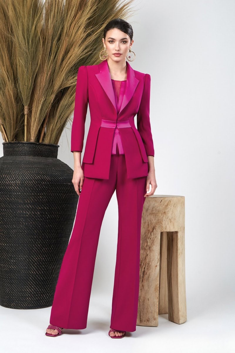 Femme portant un tailleur rose fuchsia chic avec veste ajustée et pantalon large, idéale pour un look professionnel ou sophistiqué.