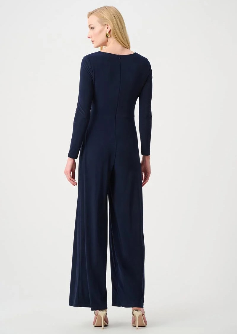 Une femme élégante portant une combinaison pantalon bleue marine, vue de dos, sur un fond blanc. Style sophistiqué, parfait pour des occasions formelles ou professionnelles.