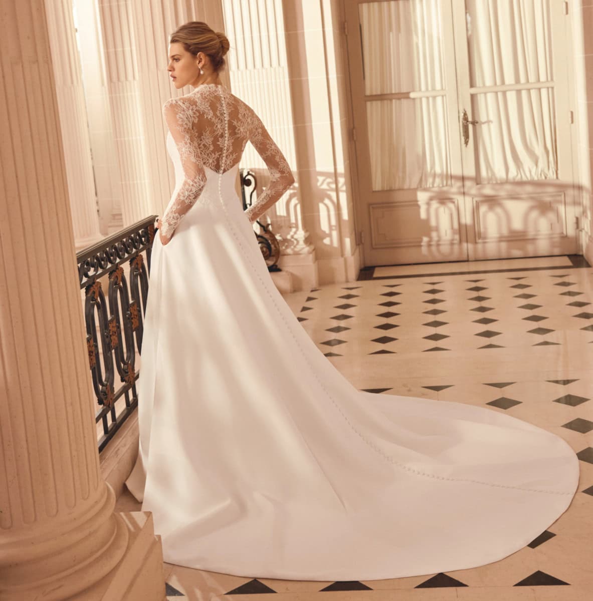 Robe de mariée élégante avec dentelle transparente et longue traîne dans un intérieur lumineux et sophistiqué.