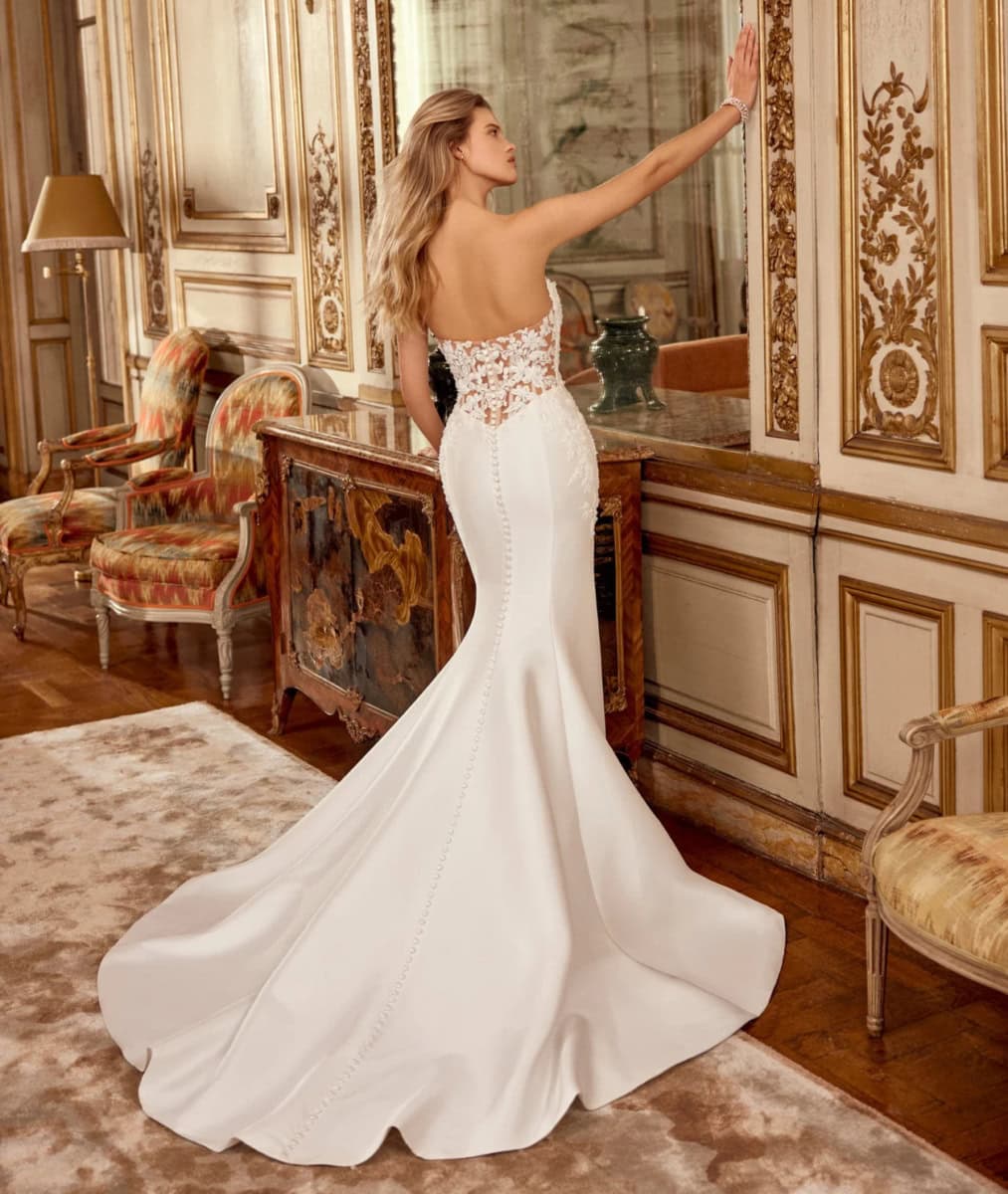 Robe de mariée élégante avec dos en dentelle et traîne longue dans un décor luxueux classique.