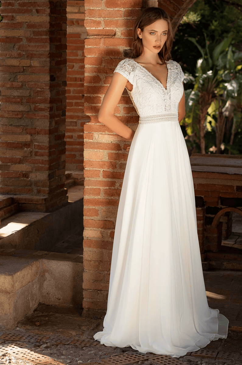 Robe de mariée élégante avec dentelle sur le haut et jupe fluide en tissu léger, idéale pour un mariage romantique en plein air.