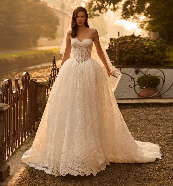 Tage de mariage élégants avec une robe de mariée en dentelle blanche, ajustée à la taille, avec un corsage en dentelle et une longue traîne, dans un décor romantique en plein air au coucher du.