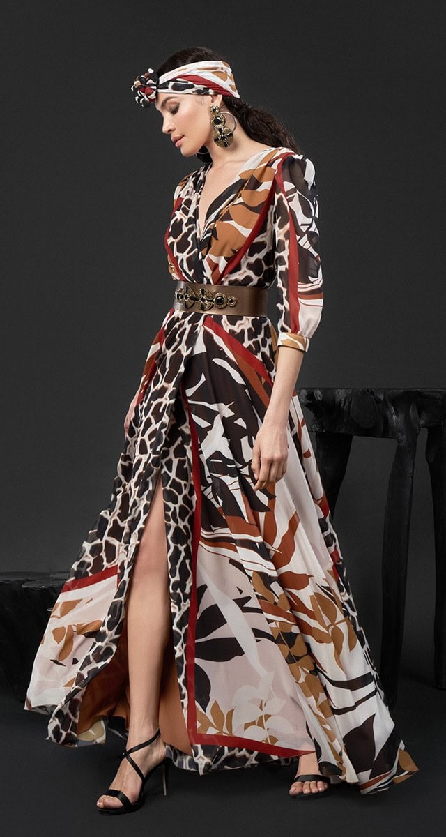 Femme portant une robe longue à motifs sauvages, avec un bandeau assorti, dans un style bohème chic, sur fond gris foncé.