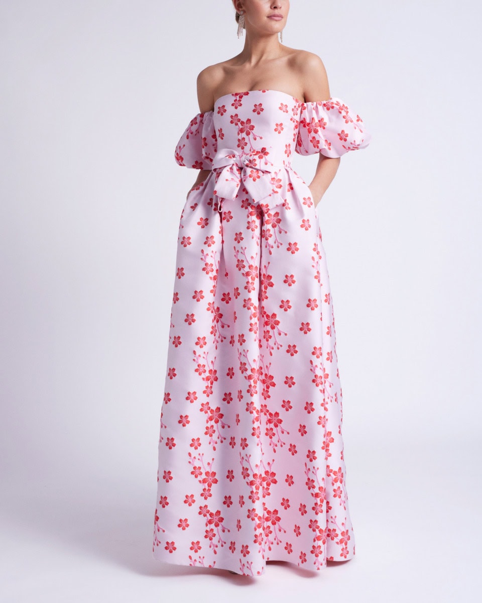 Robe longue blanche à motifs floraux rouges, style bohème, avec épaules dénudées et manches bouffantes, pour un look estival élégant.
