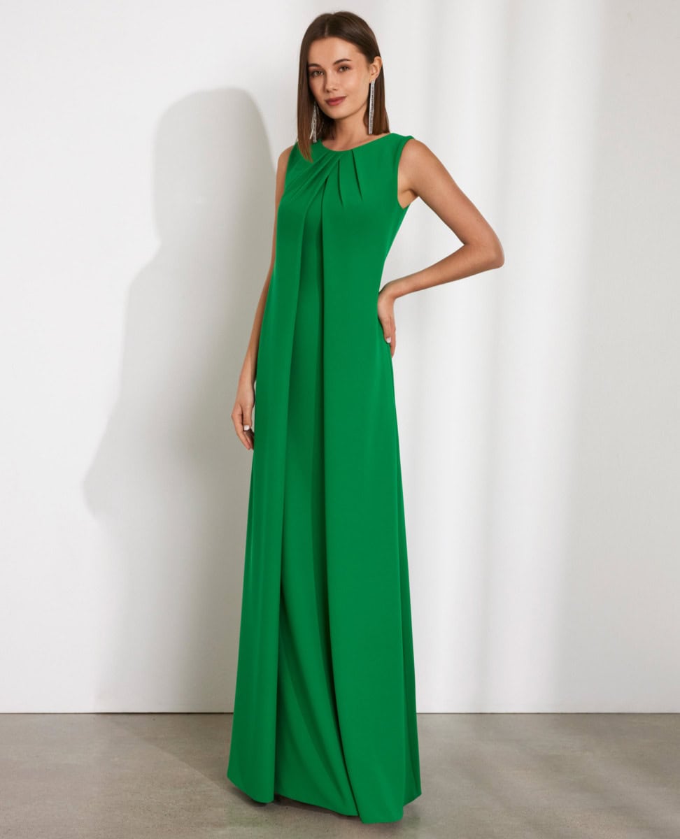 Robe longue verte élégante avec détails plissés, portée par une femme dans un studio blanc.