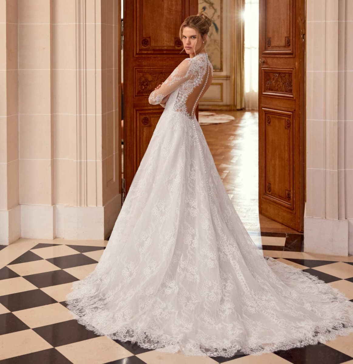 Robe de mariée en dentelle blanche avec manches longues et dos nu, élégante et sophistiquée.