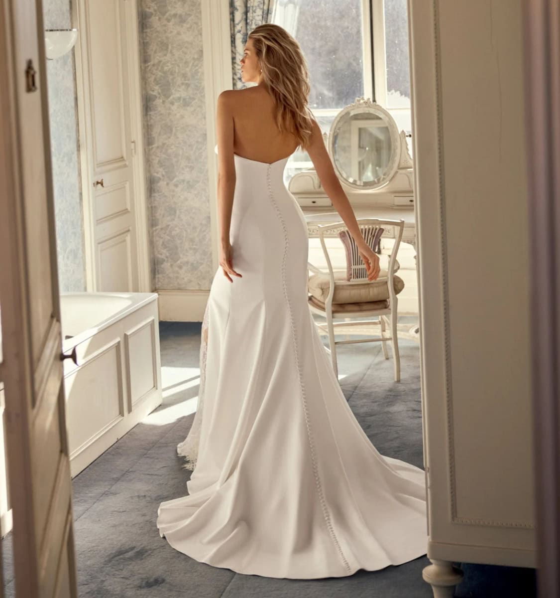 Femme portant une robe de mariée blanche élégante dans une pièce lumineuse et sophistiquée.